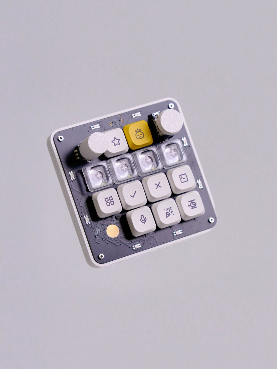 The finished OpenMicroKbd: dark PCB face in a white case, engraved keycaps, a knurled knob, a joystick, a yellow smiley key and a round gold touch pad