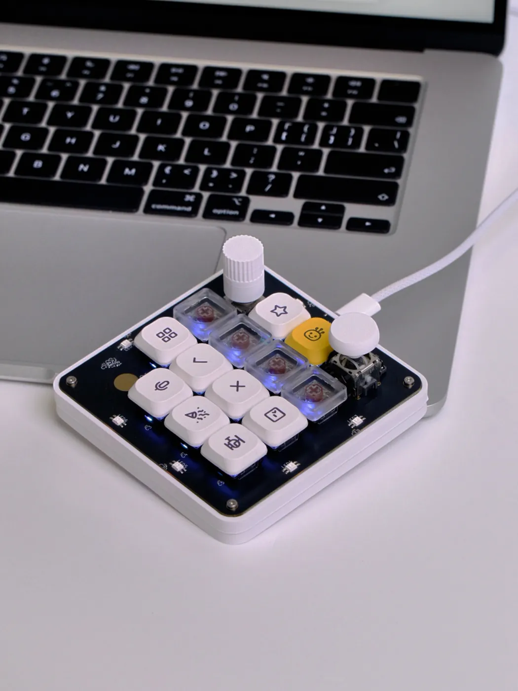 The board plugged into a MacBook over USB-C with its key lighting and underglow active